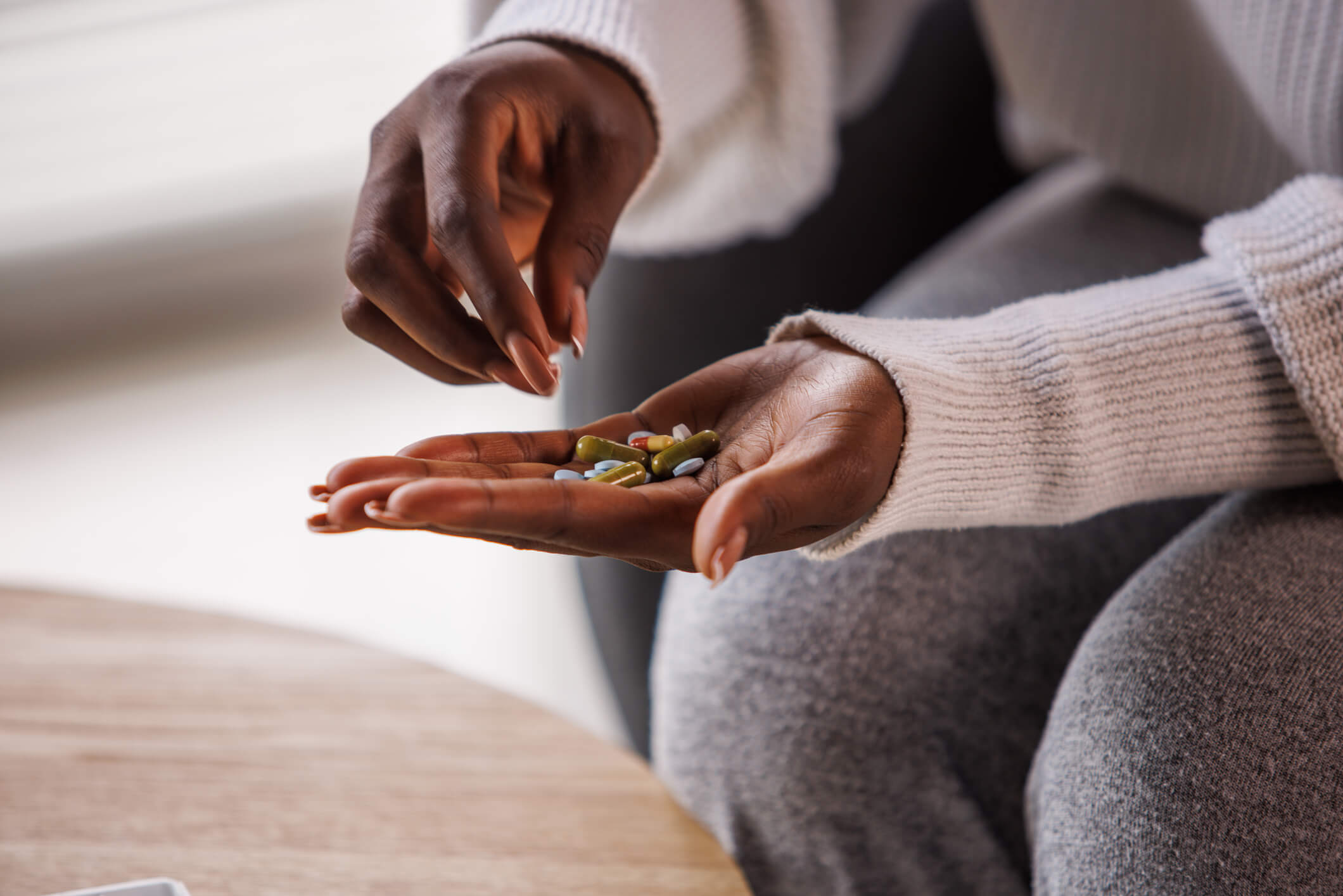 Hands of a woman sorting through pills in her palm.