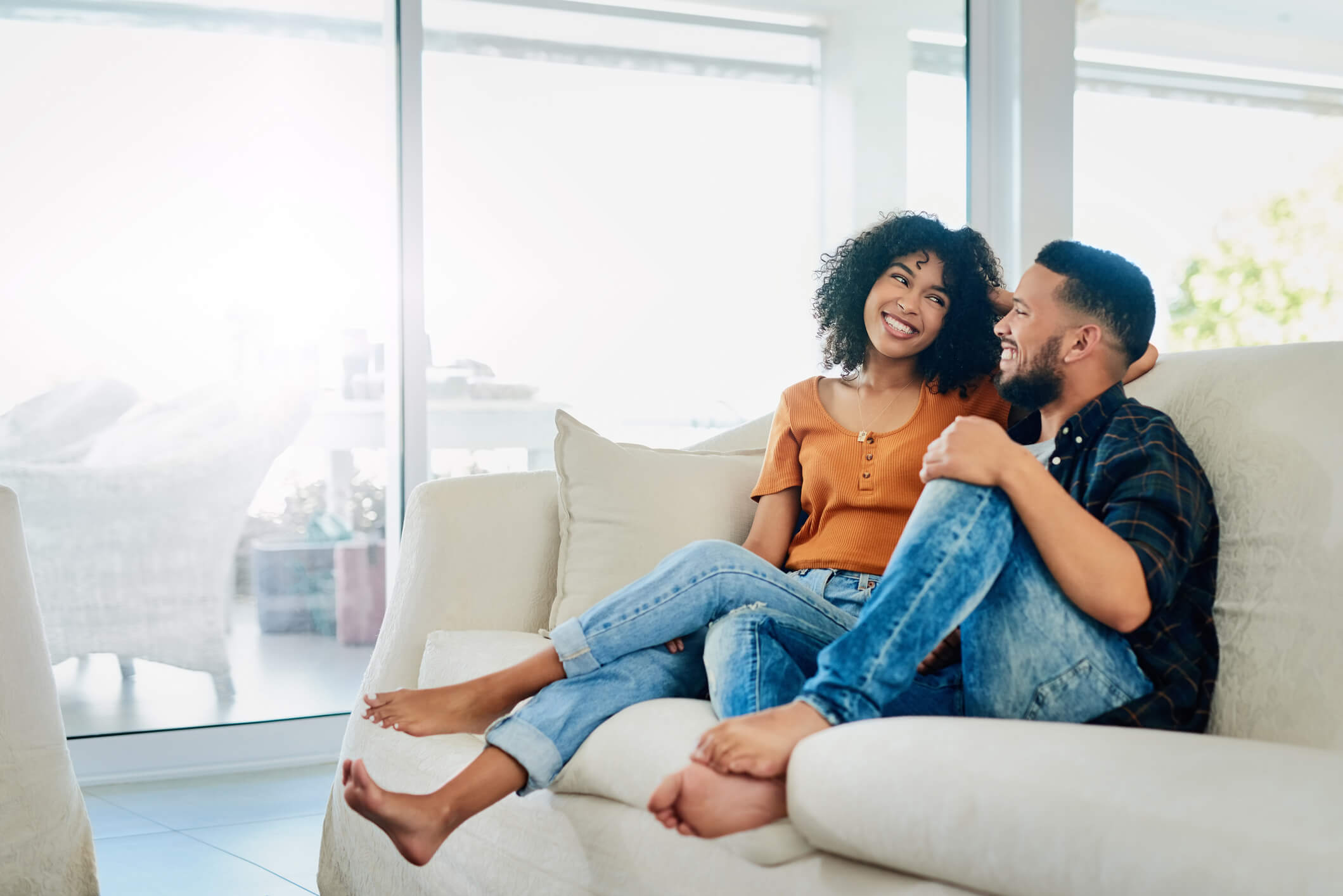 A young couple sitting next to each other comfortably on a couch.