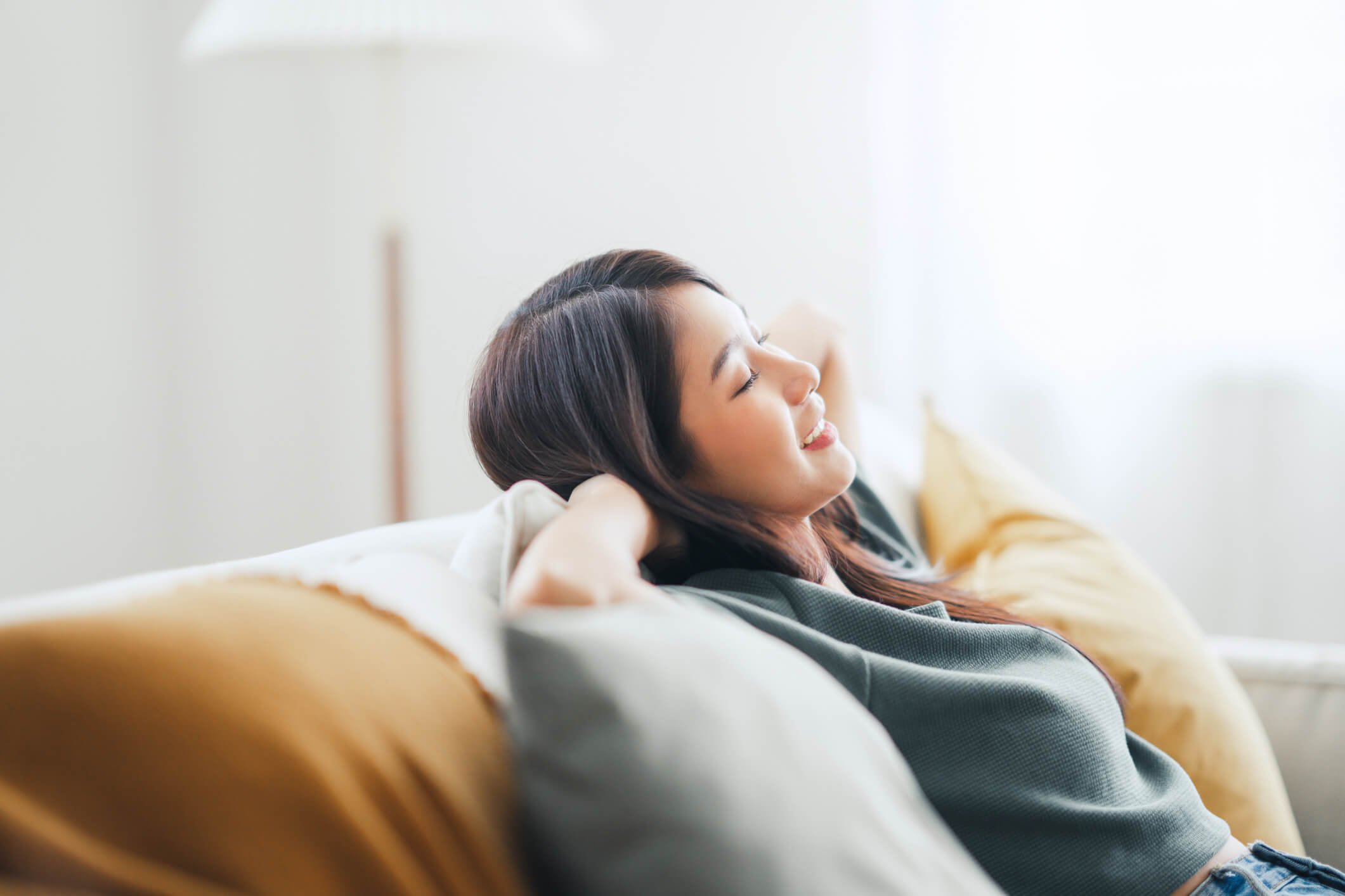 Young woman laying back on a couch relaxing.