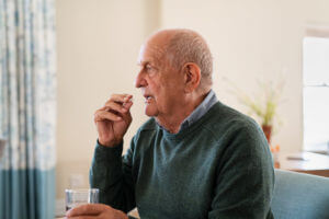 An elderly man taking his anxiety medication as part of his treatment.