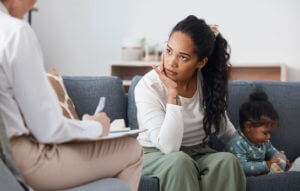 A woman with ADHD is sitting with her daughter during adult ADHD therapy with a therapist.