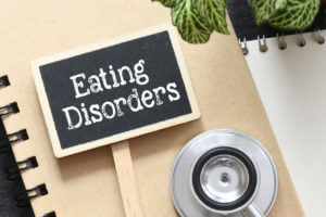 Eating Disorders words on a small chalkboard next to a stethoscope.