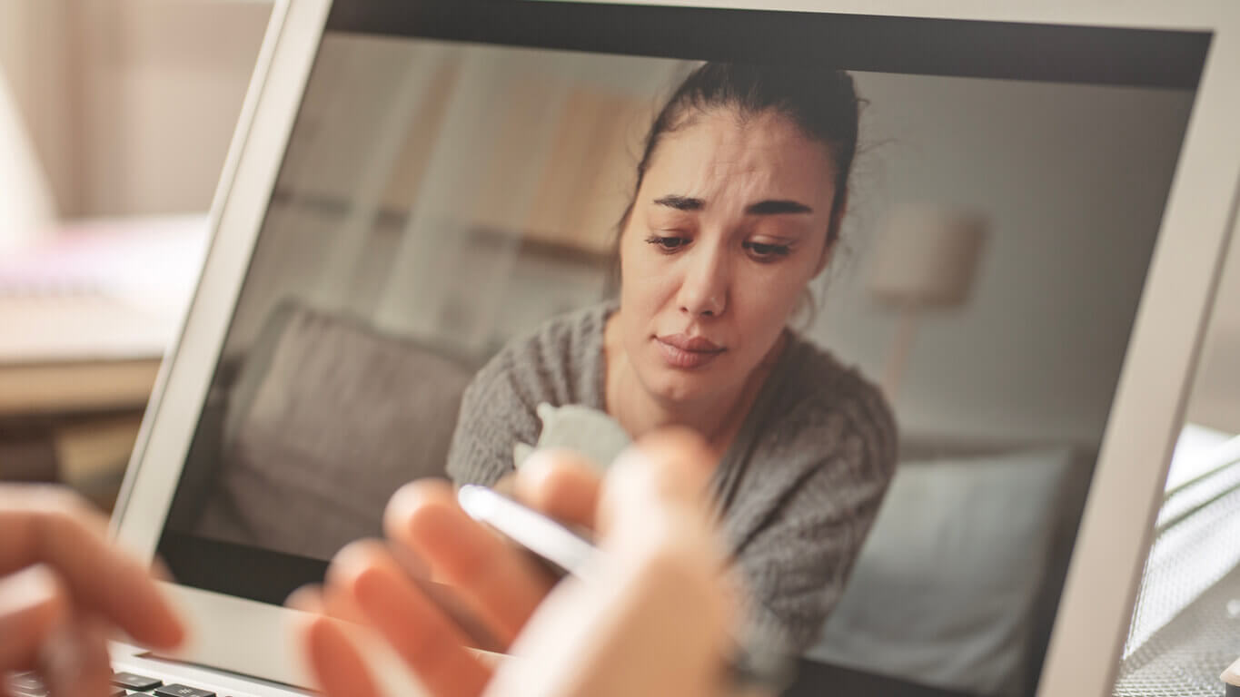 Therapist calms down emotional crying woman patient with TRD depression by video call on computer.
