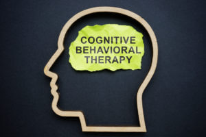 Outline of the head and inscription Cognitive behavioral therapy CBT on a piece of paper.